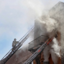 Firefighter climbing ladder at scene of building fire, West 115th Street, Between Frederick Douglas Blvd and Adam Clayton Powell Blvd, NYC.