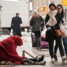 People walking past homeless man sitting on sidewalk on Seventh Ave between 50th and 51st Streets, NYC.